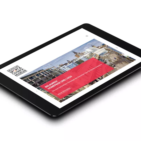 The homepage of the German Sports & Olympic Museum can be seen on a tablet. A red banner announces the relaunch of the homepage and logo