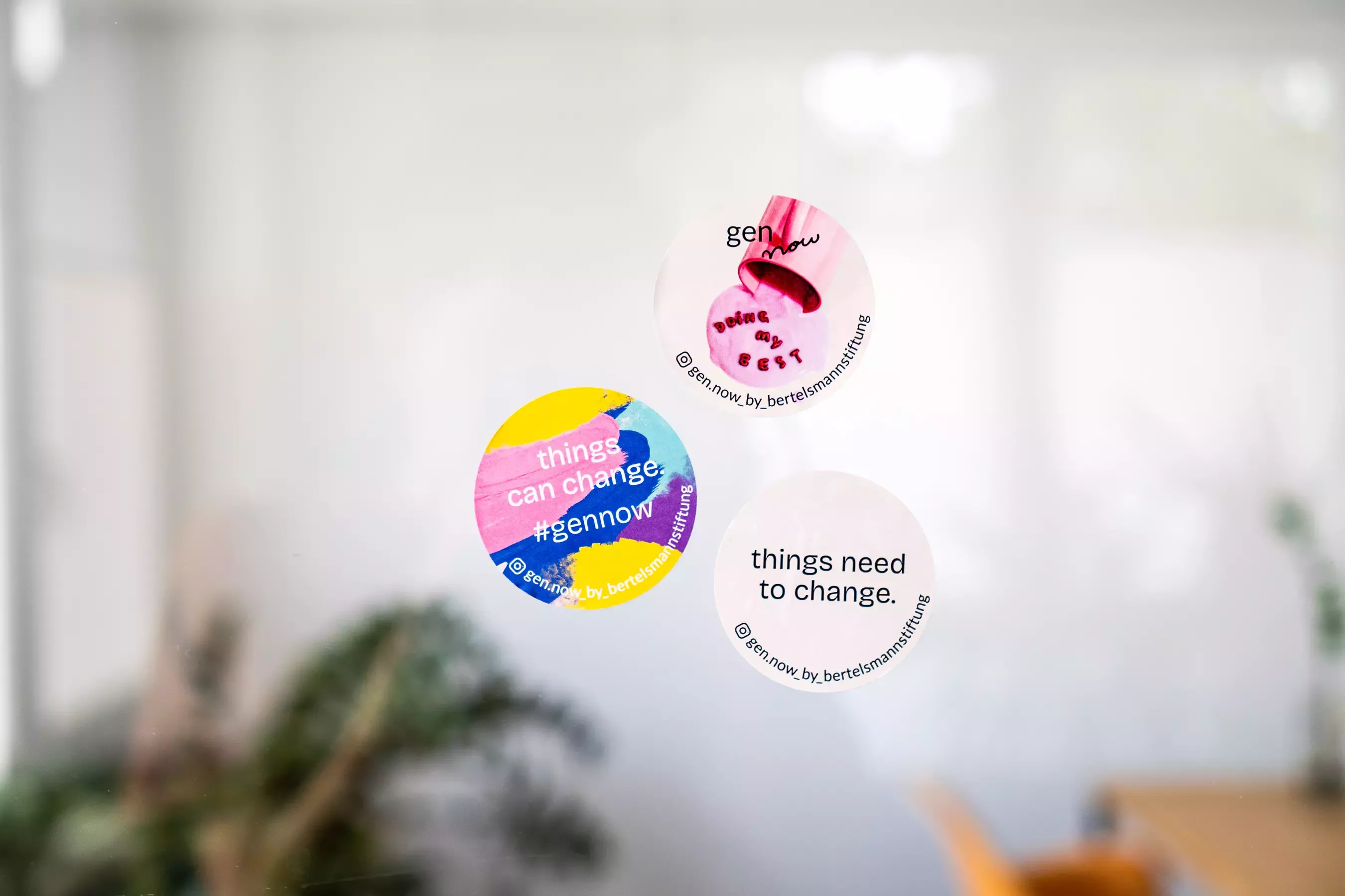 Three round stickers with gen now designs and texts such as \