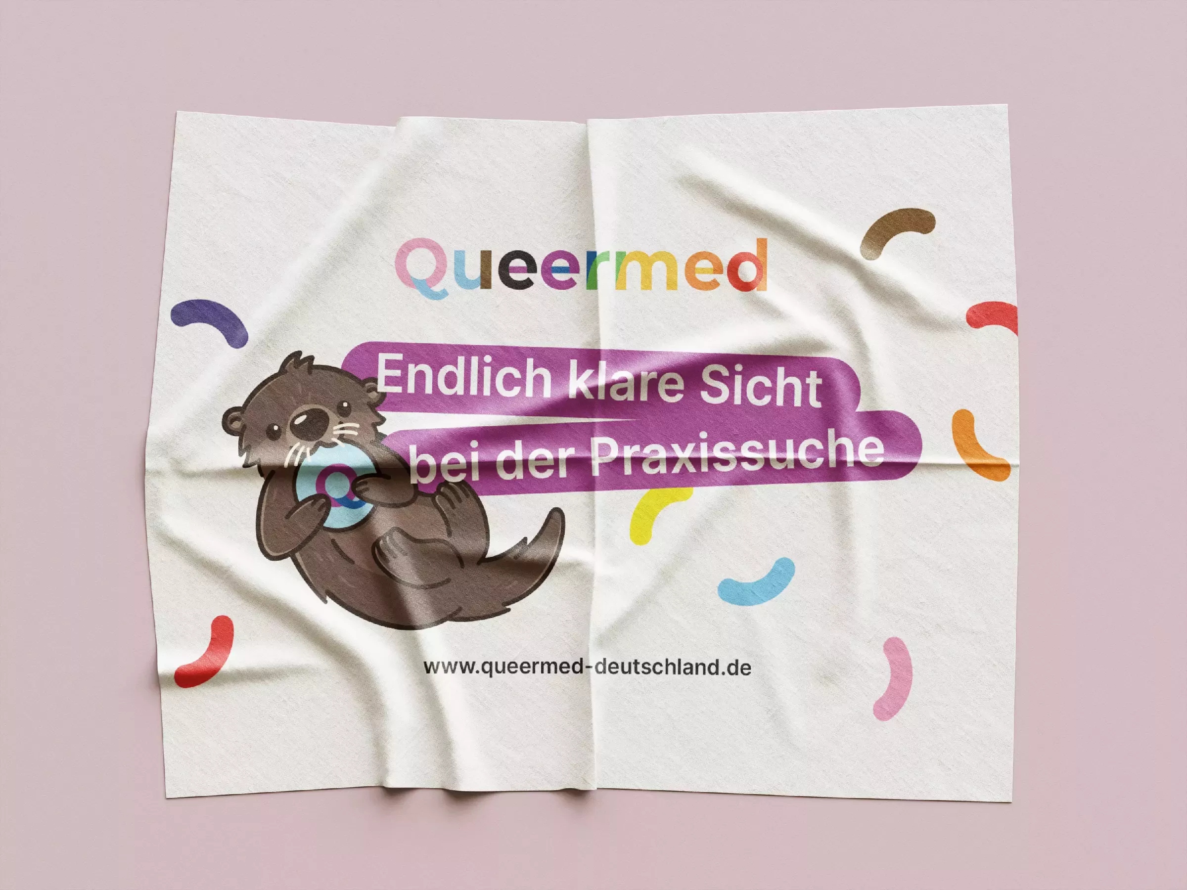 Folded glasses cleaning cloth on a pink background with an otter illustration, colorful \