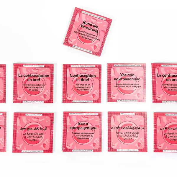 Several information brochures designed to look like condom packaging with a red background, labeled in various languages with information on contraception in Switzerland