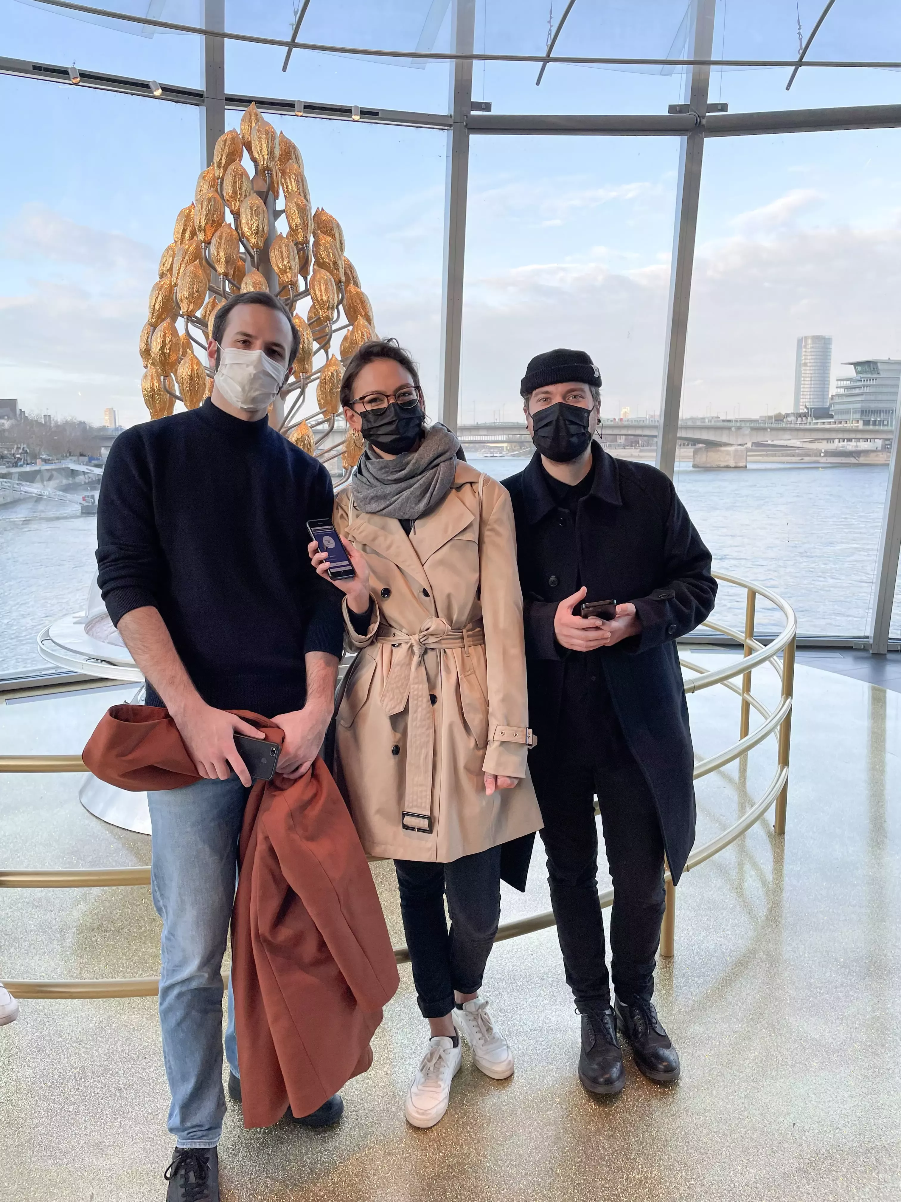 Steffen, Lea und Tobi mit Masken posieren im Schokoladenmuseum Köln vor dem goldenen Schokobrunnen