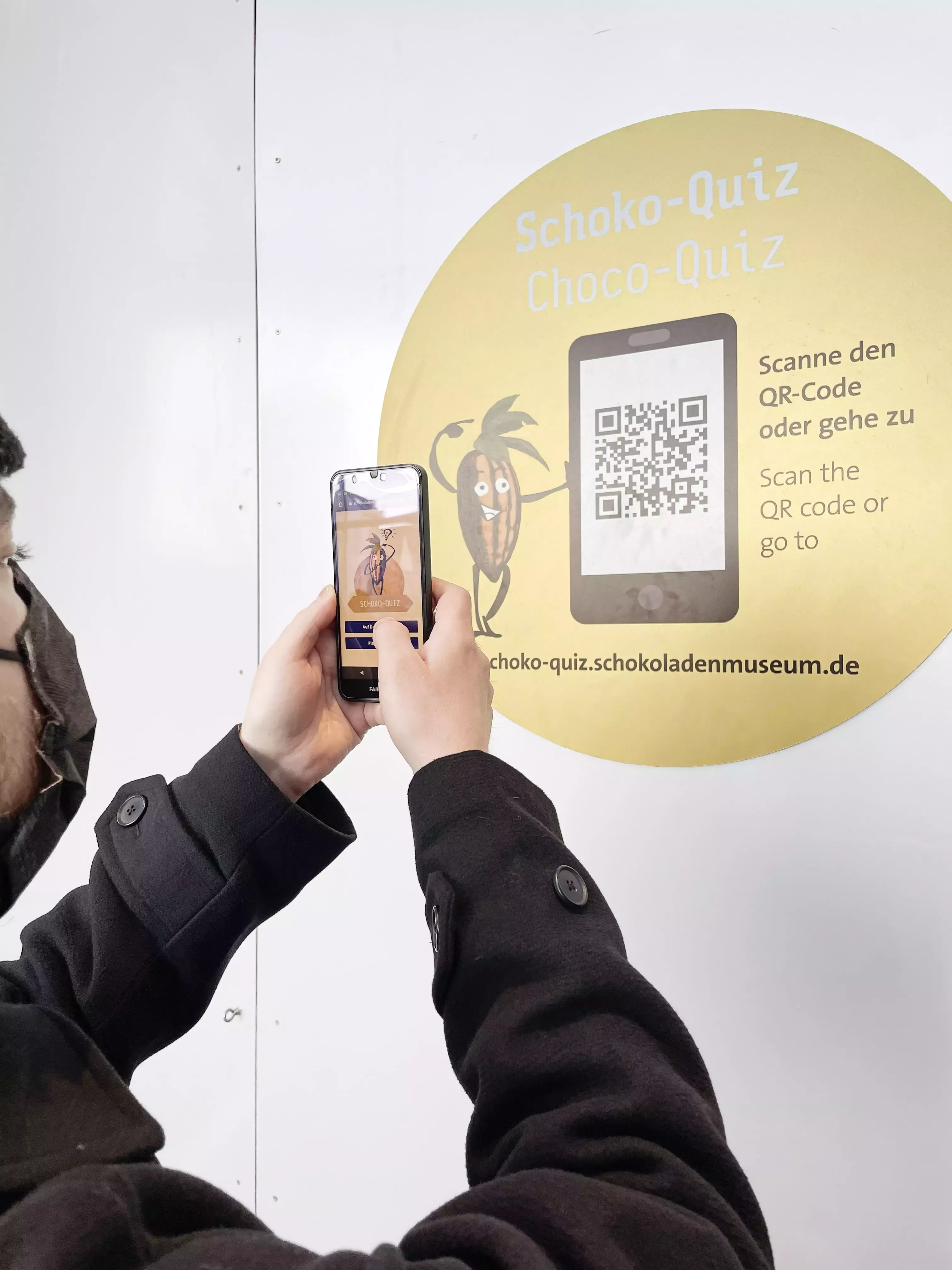 Person scannt mit dem Smartphone einen QR-Code für das „Schoko-Quiz“