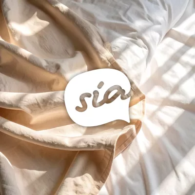 Beigefarbene und weiße Bettwäsche im Sonnenlicht mit Logo \